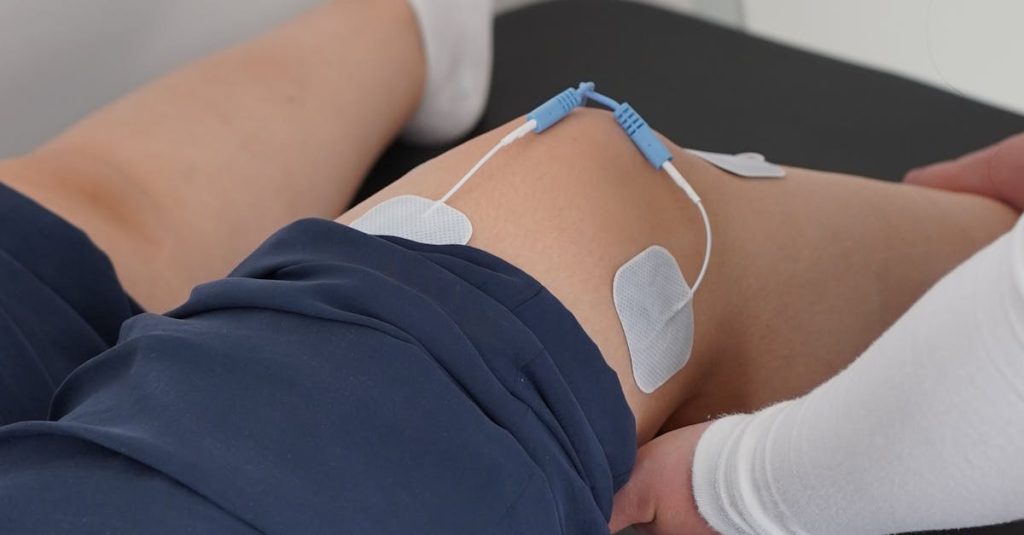 Electrotherapy applied during a knee physiotherapy session for muscle recovery.